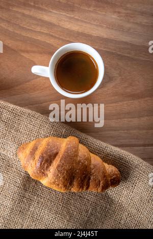 Croissant mit Espresso in weißer Tasse, Draufsicht Stockfoto