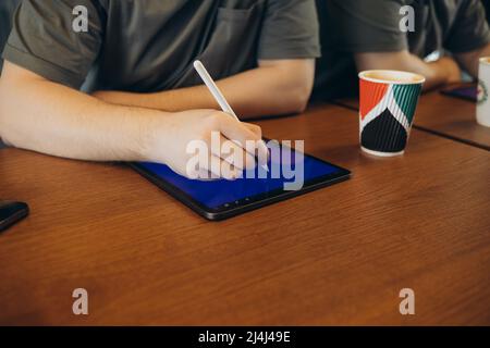 Junge kreative Web-Designer in Casualwear Kaffee mit Cookies Und zeichnen mit Stift auf Tablet beim Überarbeiten neu Website Stockfoto