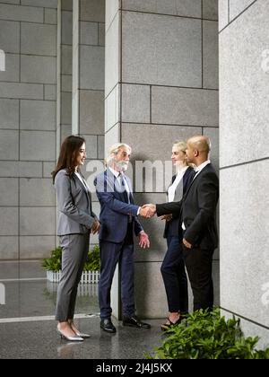 Multinationalen und multiethnischen Geschäft Leute treffen die Hände schütteln in der Lobby des modernen Bürogebäude. Stockfoto