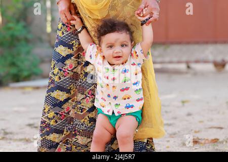 Nahaufnahme eines Portraitfotos eines kleinen neugeborenen niedlichen Hindu-Babys, das mit lächelndem Gesicht die Hand der Mutter hält, indien Stockfoto