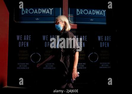 Auckland, Neuseeland. 16. April 2022. Eine Frau, die eine Maske trägt, kommt am 16. April 2022 an einem Theater im Zentrum von Auckland, Neuseeland, vorbei. Neuseeland meldete in den letzten zwei Tagen 13.636 neue Fälle in der Gemeinschaft und 30 Todesfälle von COVID-19, teilte das Gesundheitsministerium in einer Erklärung am Samstag mit. Kredit: Zhao Gang/Xinhua/Alamy Live Nachrichten Stockfoto