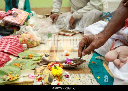 Eine Hand Durchführung hinduistischen Ritual pooja yajna innen mit Blumen und Messingutensilien. Stockfoto