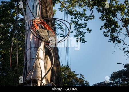 Strommasten mit überfüllten Drähten und Verteilerkästen in Indien. Stockfoto