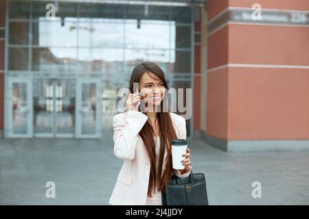 Geschäftsfrau Mit Telefon In Büronähe. Porträt Einer Lächelnden Frau, Die Im Freien Steht Und Am Telefon Spricht. Telefonkommunikation. Stockfoto