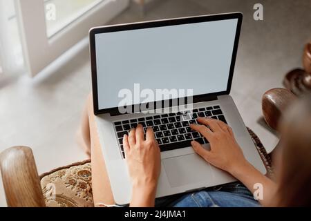 Frau, die zu Hause online an einem Laptop arbeitet. Frau, die einen Laptop zum Suchen im Internet und zum Durchsuchen von Informationen verwendet. Fernunterricht. Freiberufler Stockfoto