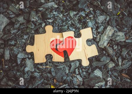 Nahaufnahme von zwei Puzzle-Teilen, die ein Herz auf Glut bilden. Liebe, Wiedervereinigung Stockfoto