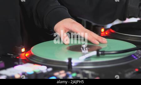 DJs spielen Platten in der Disco. Art. Nahaufnahme der Hand des DJs auf dem Mixer. Leuchtendes Musikpanel auf einer Party. Die Arbeit von Musikern in einem Nachtclub Stockfoto