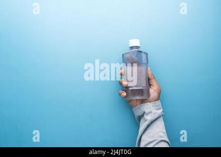 Halten Sie einen Behälter für Mundwasser mit der Hand Stockfoto