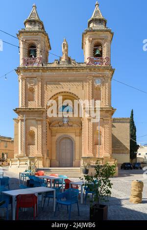 Marsaxlokk, Malta - März 23. 2022: Tisch und Stühle vor der Kirche unserer Lieben Frau von Pompei, die 1890 gegründet wurde und die Pfarrkirche ist Stockfoto