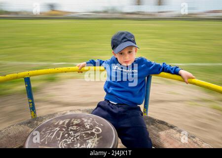 Netter kleiner Junge, der Spaß auf dem Spielplatz hat Stockfoto