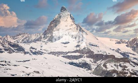 Ikonischer Blick auf den schneebedeckten Matterhorn-Gipfel mit blauem Himmel und Wolken, Zermatt, Schweiz Stockfoto
