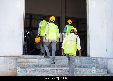 Rückansicht einer Gruppe von Industriearbeitern, die zur Arbeit in der Fabrik kommen - Konzept der täglichen Einsätze, Beschäftigung und Arbeitsplätze. Stockfoto