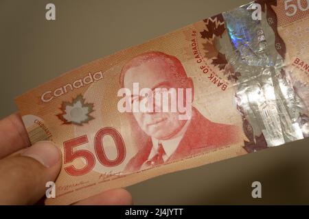 Personen geben die Währung des Kanada - eine rote fünfzig (50) Dollar-Note auf einem braunen Hintergrund ausgebreitet. Geldwechsel. Stockfoto