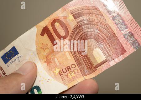 Personen geben die Währung des England im Vereinigten Königreich - eine rote zehn (10) Pfund-Note auf einem braunen Hintergrund. Geldwechsel. Stockfoto