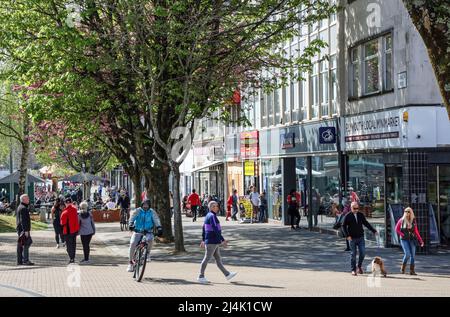 Der Armada Way von Plymouth liegt in der Hauptfußgängerzone mit Geschäften und Straßencafés. Shopper genießen Ostersamstag 2022. Bäume bringen Colo Stockfoto