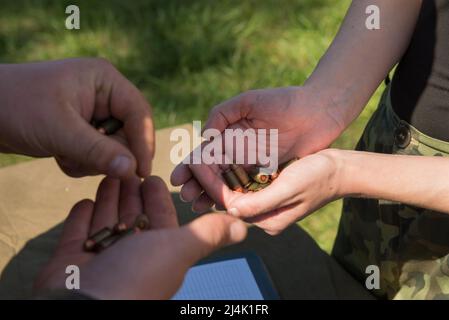 Halten Kugeln für ein Gewehr oder eine Pistole in einer Frauenhand vor dem Schießen, militärische Ausbildung. Nahaufnahme von oben Stockfoto