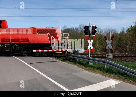 Vorbeifahrende Güterbahn mit Lokomotive Gravity 10 BB am Bahnübergang Stockfoto