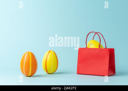 Osterei in Einkaufstasche auf blauem Hintergrund. Minimales Osterkonzept. Kreatives Happy Easter oder Frühlingslayout. Stockfoto