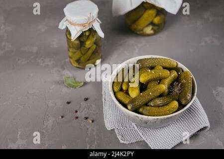 Eingelegte Gurken, Gewürze und Knoblauch auf einem grauen Betontisch konservieren Stockfoto