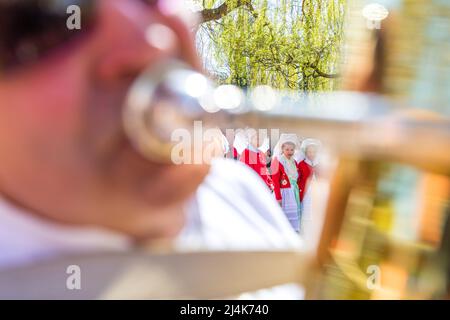 16. April 2022, Brandenburg, Lübben: Kinder der Kita Spreewald und der Liuba-Grundschule in Lübben stehen bei der Übergabe des Rudel am Lübbener Hafen in traditionellen Spreewald-Kostümen. Traditionell wird am Osterwochenende in Lübben der "Frühlingsbeginn" gefeiert. Am Hafen findet die rudel- und Paddelübergabe zum offiziellen Start der Saison der Kahn- und Paddelboote statt. Ein rudel ist eine hölzerne Vorrichtung, die von Bargemen benutzt wird, um ihren Lastkahn durch die Wasserwege des Spreewalds zu bewegen. Diese Aktivität wird als „Aufnahme“ bezeichnet. Stockfoto