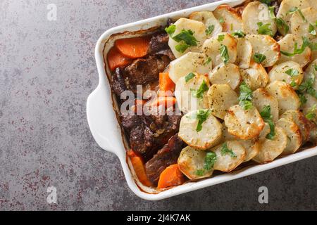 Lancashire Hot Pot, Lamm und Gemüse mit geschnittenen Kartoffeln und im Ofen gebacken Nahaufnahme in der Auflaufform auf dem Tisch. Horizontale Draufsicht von A Stockfoto