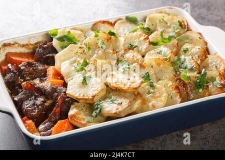 Hausgemachter Fleischeintopf mit Kartoffelscheiben in Keramikschüssel, traditionelles britisches Pub-Essen in der Auflaufform auf dem Tisch. Horizontal Stockfoto