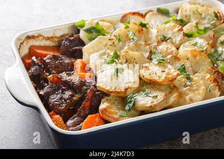 Lancashire Hot Pot, Lamm und Gemüse mit geschnittenen Kartoffeln und im Ofen gebacken Nahaufnahme in der Auflaufform auf dem Tisch. Horizontal Stockfoto