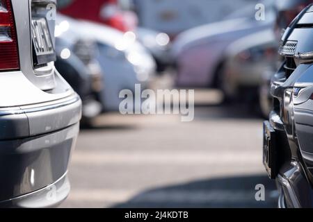 Zwei Autos auf einem Parkplatz. Links ein Auto mit einem Deutschen, rechts ein holländisches Nummernschild. Verschwommene Autos im Hintergrund, Ort für Text Stockfoto