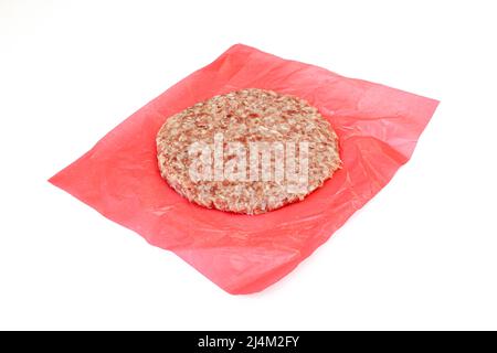 Rohes Rindfleisch-Patty auf rotem Kunststoffpapier isoliert auf weißem Hintergrund Stockfoto
