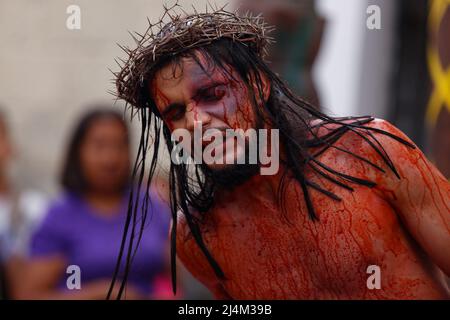 CARACAS, VENEZUELA - 16. APRIL: Ein Schauspieler, der Jesus Christus verkörpert, wird von einem anderen Schauspieler geißelt, der römische Soldaten porträtiert, als sie am 15. April 2022 in der Karfreitagsprozession in Caracas' Petare-Shantytown das Leiden Jesu Christi nachspielen. (Foto: Pedro Mattey/PxImages) Stockfoto