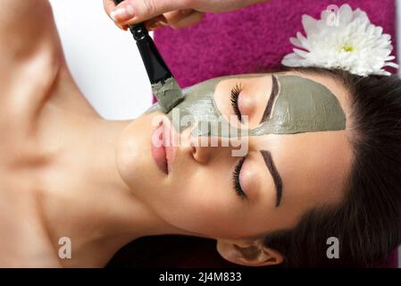 Frau mit Gesichtsmaske aus Lehm im Beauty Spa. Hautpflege. Schönheitskonzept. Close-up-Porträt des schönen Mädchen Anwendung Gesichtsmaske.Gesichtsbehandlung. Cosm Stockfoto