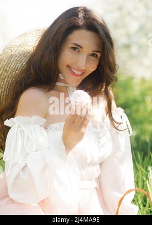 Frühlingsporträt eines schönen Mädchens in einem erstaunlichen Kleid, das den Frühling in einem frisch blühenden Garten an einem sonnigen, frischen Tag genießt. Stockfoto