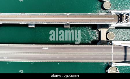 Sommeransicht von einem Hubschrauber. Aktion. Eine riesige Brücke für fahrende Autos, die hoch über dem Meer und dem blauen Tageshimmel gebaut wurde. Stockfoto