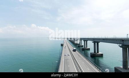 Sommeransicht von einem Hubschrauber. Aktion. Eine riesige Brücke für fahrende Autos, die hoch über dem Meer und dem blauen Tageshimmel gebaut wurde. Stockfoto