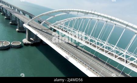 Schöne Landschaft aus einem Hubschrauber. Aktion. Der Blick von der Drohne auf die große weiße Brücke, auf der sich Autos über den Ozean bewegen. Stockfoto