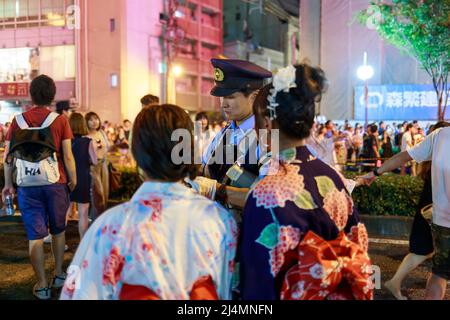 Osaka, Japan - 25. Juli 2015: Polizeibeamter gibt nach dem Tenjin Matiri-Sommerfest Anweisungen an Frauen, die Kimonos auf einer überfüllten Straße tragen Stockfoto