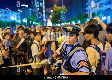 Osaka, Japan - 25. Juli 2015: Polizeibeamter leitet eine Menschenmenge an, die das Sommerfest von Tenjin Mtsuri verlässt Stockfoto