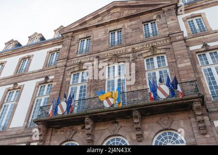 Liberte, Egalite, Fraternite Inschrift auf dem Rathausgebäude in Straßburg mit ukrainischen nationalen und französischen Nationalflaggen, die an der Fassade winken Stockfoto