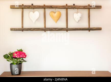 Alte Holzleiter mit Herzen, die an der Wand hängen. Heimtextilien. Stockfoto