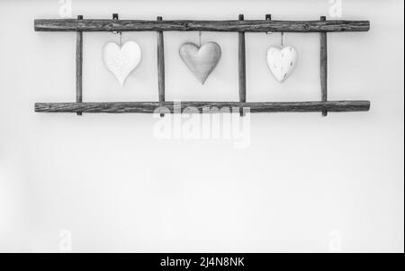 Alte Holzleiter mit Herzen, die an der Wand hängen. Heimtextilien. Stockfoto