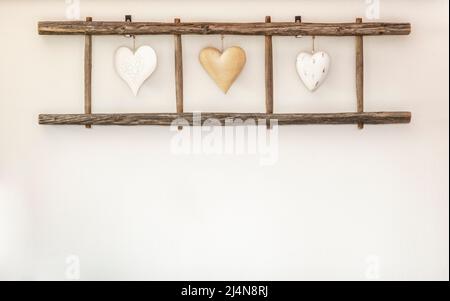 Alte Holzleiter mit Herzen, die an der Wand hängen. Heimtextilien. Stockfoto