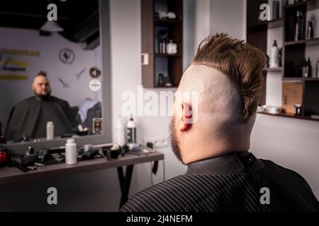 Junge trendige Mann Porträt. Punk-Stil Mann mit Mohawk Frisur vor dem Hintergrund eines Friseurladen Stockfoto