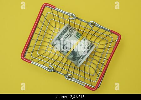 In einen Schlauch gerollte Dollars liegen in einem Einkaufskorb. Stockfoto