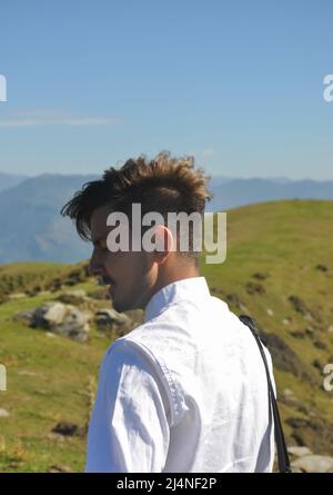 Rückansicht eines gut aussehenden jungen Mannes, der mit geschlossenen Augen in der Natur steht Stockfoto