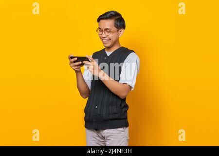 Porträt eines glücklichen jungen asiatischen Mannes, der Videospiel auf dem Mobiltelefon spielt Stockfoto