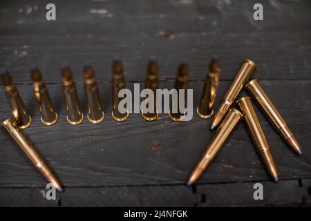 Scharfe Patronen stehen auf einer Holzkiste für das Gewehr. Stockfoto