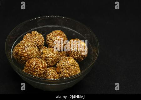 Die süßen Sesambälle befinden sich in einer Tasse. Auf schwarzem Hintergrund Stockfoto