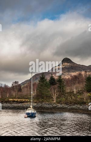 Wunderschöner Blick auf die Winterlandschaft entlang des Loch Leven in Richtung schneebedeckter Berge in der Ferne mit festgedeckter Segelyacht im Vordergrund Stockfoto