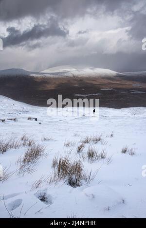 Wunderschöne Winterlandschaft von der Bergspitze in den schottischen Highlands hinunter in Richtung Rannoch Moor während Schneesturm und Spindrift von der Bergspitze hinein Stockfoto