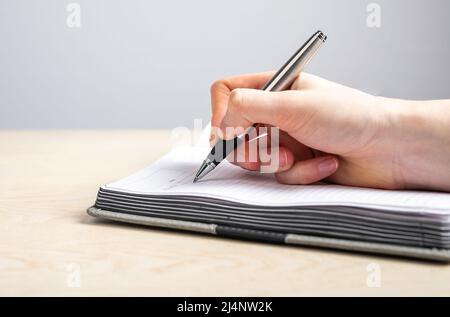 Frau Hand Nahaufnahme Notizen im Planer. Weibliche Schreiben mit Stift Informationen, Erinnerungen, Zeitplan in Tagebuch. Handschrift. Hochwertige Fotos Stockfoto